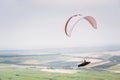 White orange paraglide with a paraglider in a cocoon against the background of fields of the sky and clouds. Paragliding