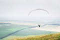 White orange paraglide with a paraglider in a cocoon against the background of fields of the sky and clouds. Paragliding