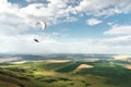 White orange paraglide with a paraglider in a cocoon against the background of fields of the sky and clouds. Paragliding Royalty Free Stock Photo