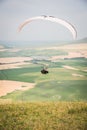 White orange paraglide with a paraglider in a cocoon against the background of fields of the sky and clouds. Paragliding