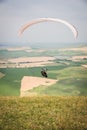 White orange paraglide with a paraglider in a cocoon against the background of fields of the sky and clouds. Paragliding Royalty Free Stock Photo