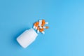 White and orange pills, tablets and white bottle on blue background Royalty Free Stock Photo