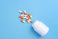 White and orange pills, tablets and white bottle on blue background Royalty Free Stock Photo