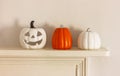 white and orange pumpkin figures and candle holder jack-o-lantern on a shelf. Home decor for Halloween Royalty Free Stock Photo