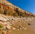 White and orange rockfalls litter the beach beneath the white, red and orange stratified cliffs at Old Hunstanton, Norfolk, UK