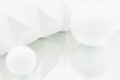White origami background reflected in mirror with two white spheres of different sizes