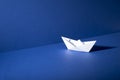 White Origami Boat on Blue Floor and Wall Background Royalty Free Stock Photo