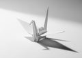 White origami crane on a light gray surface, casting a distinct shadow Royalty Free Stock Photo
