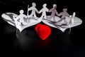 White origami people are flying on the white origami wings of the red heart. International Human Solidarity Day