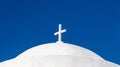 White orthodox greek church with cross on clear blue sky background. Summer vacation destination Royalty Free Stock Photo