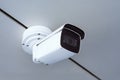 White outdoor and indoor security camera with adjustable mount and clear lens installed on a gray ceiling, representing advanced Royalty Free Stock Photo