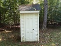 White outhouse or shed with door and trees