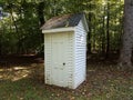 White outhouse or shed with door and trees