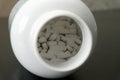 White tablets spilling out of a bottle on a dark surface Royalty Free Stock Photo