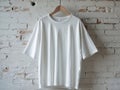 White oversized tee shirt hanging brick wall studio backdrop mockup. Royalty Free Stock Photo