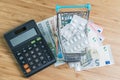 White package pills in miniature shopping cart on pile of Euro banknotes money with calculator on wood table, health care, medical Royalty Free Stock Photo