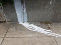 white paint dripping down grey cement wall onto sidewalk