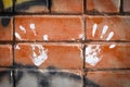 White paint prints of two hands on colourful graffity on a brick Royalty Free Stock Photo
