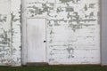 White painted brick wall with peeling white paint and closed door