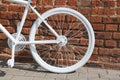 White painted decorative wheel of an old bicycle against a brick wall. Royalty Free Stock Photo