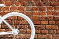 White painted decorative wheel of an old bicycle with a basket of flowers against a brick wall. Copy space Royalty Free Stock Photo