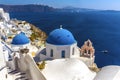 White painted houses and blue-domed churches in the village of Oia, Santorini with the backdrop of the caldera Royalty Free Stock Photo