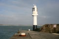 White painted lighthouse at end of breakwater Royalty Free Stock Photo