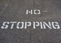 White No Stopping Sign Stenciled on Black Road Royalty Free Stock Photo