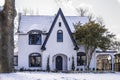 White painted upscale two story brick house in the snow and gate at drive and landscaping