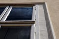 white painted wood window frame in stucco exterior wall. low angle view. old style metal hinges. dark window glass. Royalty Free Stock Photo