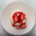 White panna cotta with strawberry in a dish on a white background. Top view