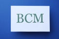 White paper with abbreviation BCM Business Continuity Management on blue background, top view Royalty Free Stock Photo