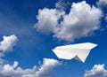 White paper plane travels in blue sky with white clouds