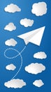 White paper airplane with start point, dash line trace and white clouds on blue air background. Clear sky travel background Royalty Free Stock Photo