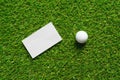 White paper background and golf ball on green grass of golf course. Royalty Free Stock Photo