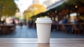 White paper biodegradable disposable cup with lid for hot drinks on a wooden table of street cafe. Tea or coffee to take Royalty Free Stock Photo