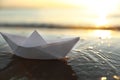 White paper boat in shallow water of sea at sunset, space for text Royalty Free Stock Photo