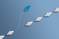 White paper boats in a row on blue background and one paperboat going in different direction