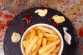 White paper bowl of french fries chipsWhite paper bowl of french fries chips potato and sauces on black stone slate over rusty Royalty Free Stock Photo