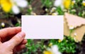 White paper business card in hand. Mockup with flowers and craft envelope in forest.Nature concepts. Wedding invitation template. Royalty Free Stock Photo