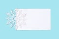 White paper card decorated with snowflakes on light blue background. Royalty Free Stock Photo