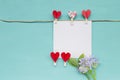 White paper card with red paper heart clip and purple flower on blue background Royalty Free Stock Photo