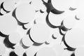 White paper circles different size as mess swarm random abstract pattern in hard light with contrast black strict shadows.