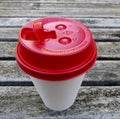 White paper coffee cup with red travel lid on wooden table Royalty Free Stock Photo