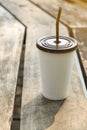 White paper cup with brown tube on wooden background