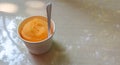 White paper cup with orange juice smoothie blended inside the paper cup, With Plastic spoon Royalty Free Stock Photo