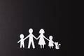 White paper cut out of family with two children and cat and copy space on black background Royalty Free Stock Photo