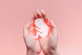 White paper embryo silhouette in woman hands. Pastel pink background with copy space. Pregnancy and abortion