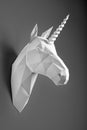 White paper geometrical shaped unicorn`s head hanging on black wall.