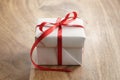 White paper gift box with thin red ribbon bow on old wood table Royalty Free Stock Photo